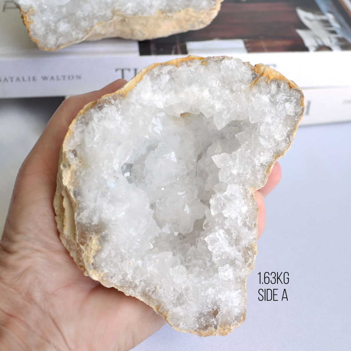 Hand holding a crystal geode on a plain background