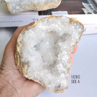 Hand holding a crystal geode on a plain background