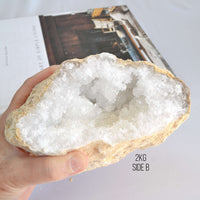 Hand holding a large crystal geode on a neutral background
