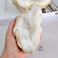 hand holding large clear quartz crystal geode by the essential collection crystals