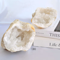 Two crystal geodes on a white surface with a book underneath.