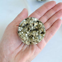 Hand holding a large pyrite crystal with a white background