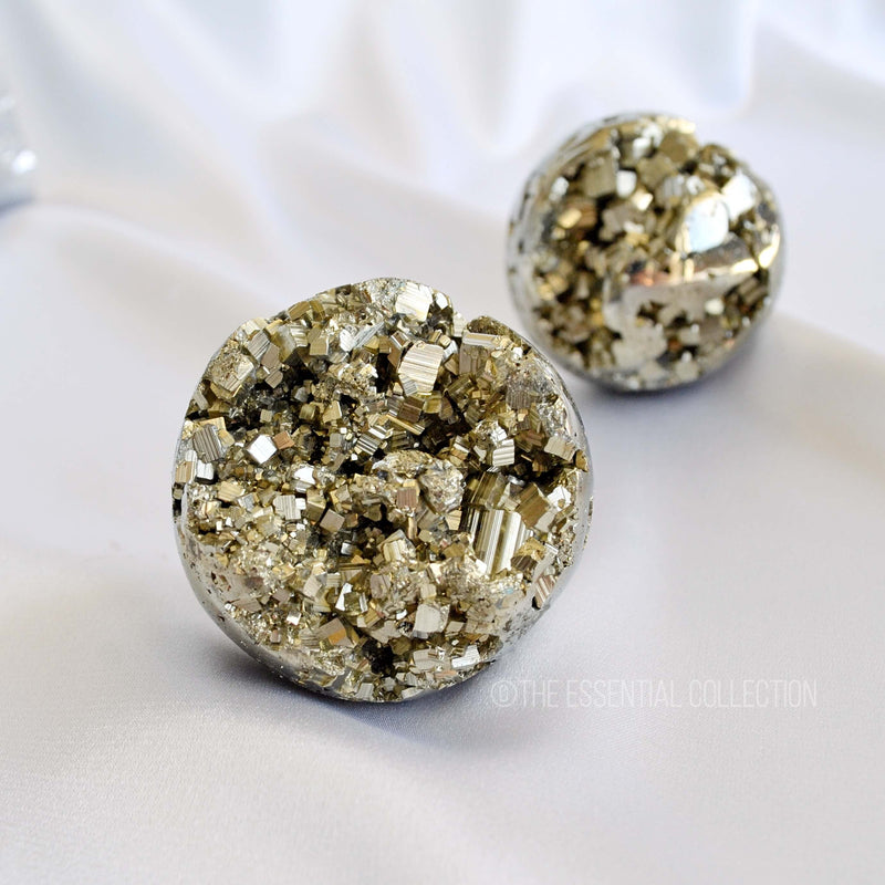 Round pyrite stones with a textured surface on a white background, branded 'The Essential Collection'.