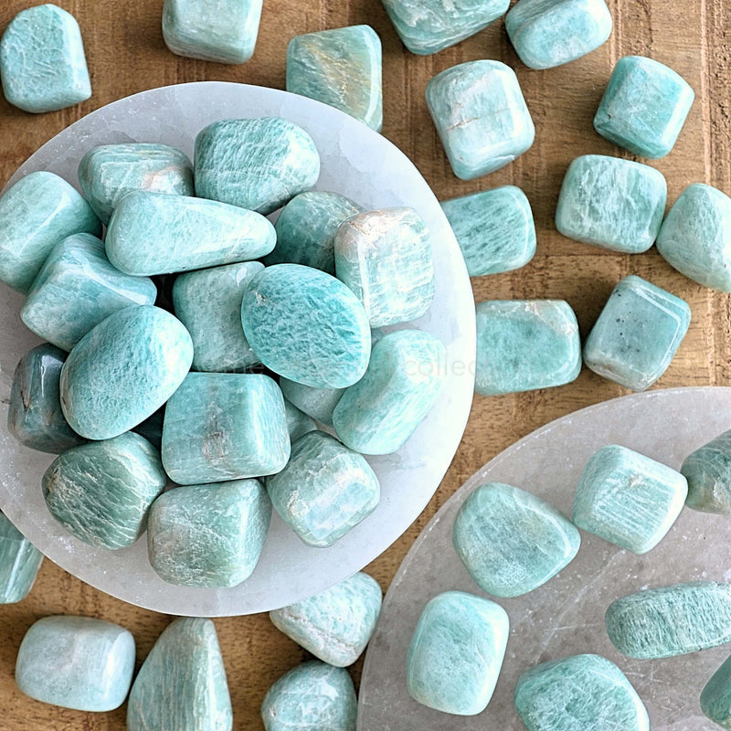 amazonite tumbled crystals in white selenite bowl on wood table