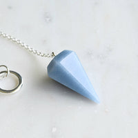 blue angelite crystal pendulum white background