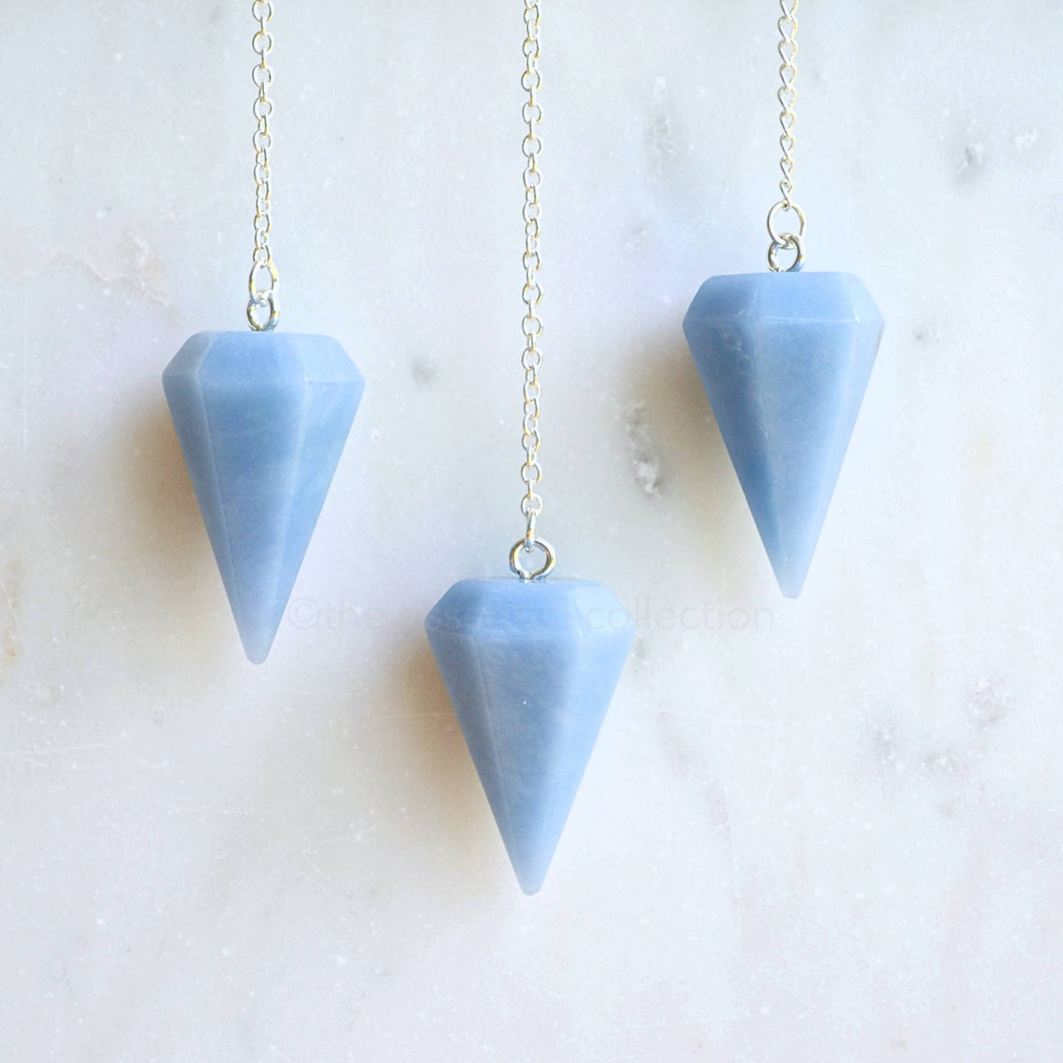 3 angelite crystal pendulums white marble background