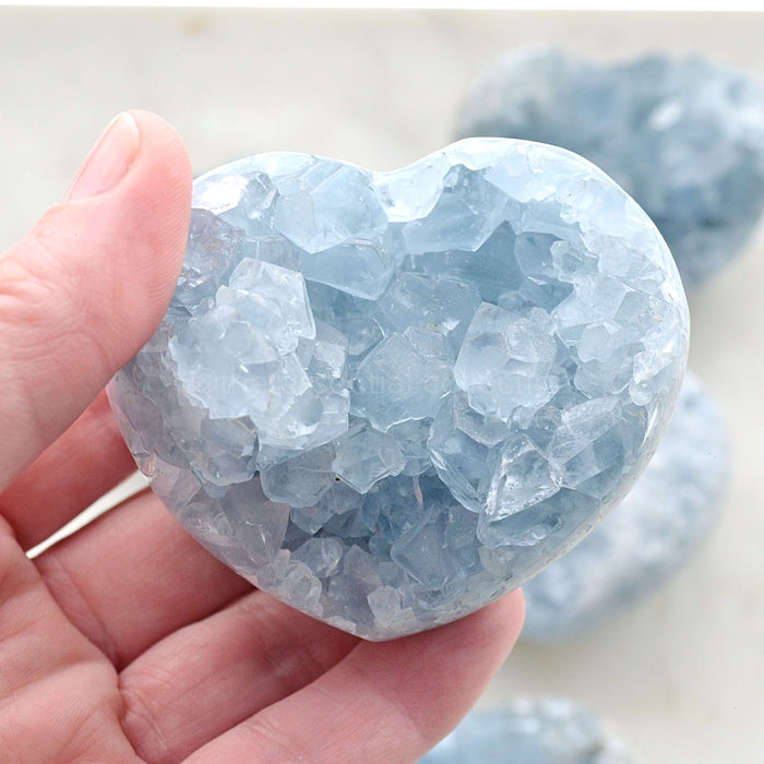 raw Celestite heart crystal in hand