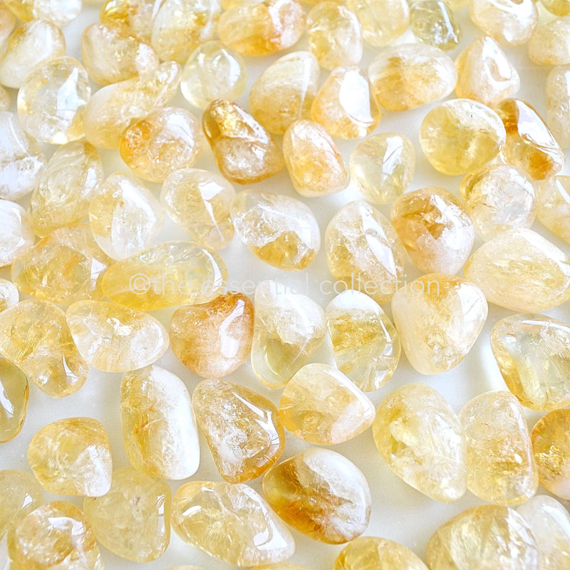 bright yellow citrine tumbled crystals gemstones spread around on white background by the essential collection Australia