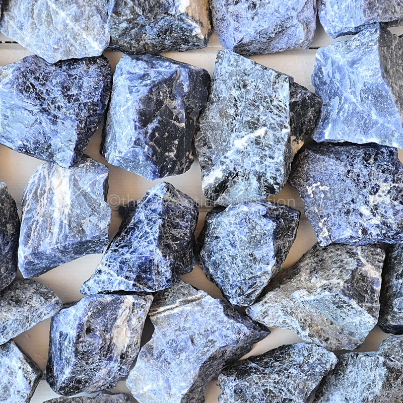large raw rough sodalite crystals in pile white background