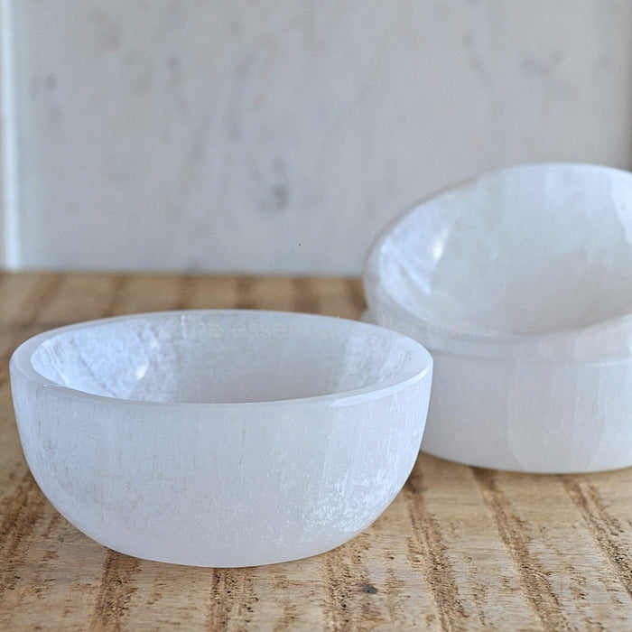 white selenite bowls on wood table with white background
