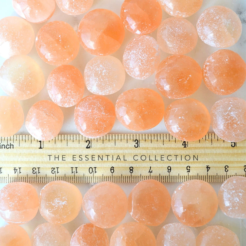 orange selenite tumbled crystals by a ruler showing the size