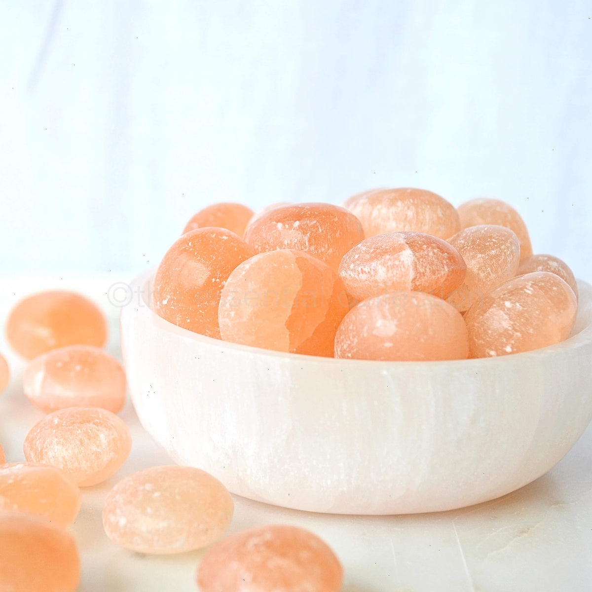 orange selenite tumbled crystals in bowl with white background