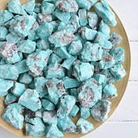 raw rough amazonite crystals in wood bowl white background
