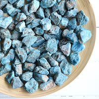 raw rough blue apatite crystals gemstones stones in wood bowl