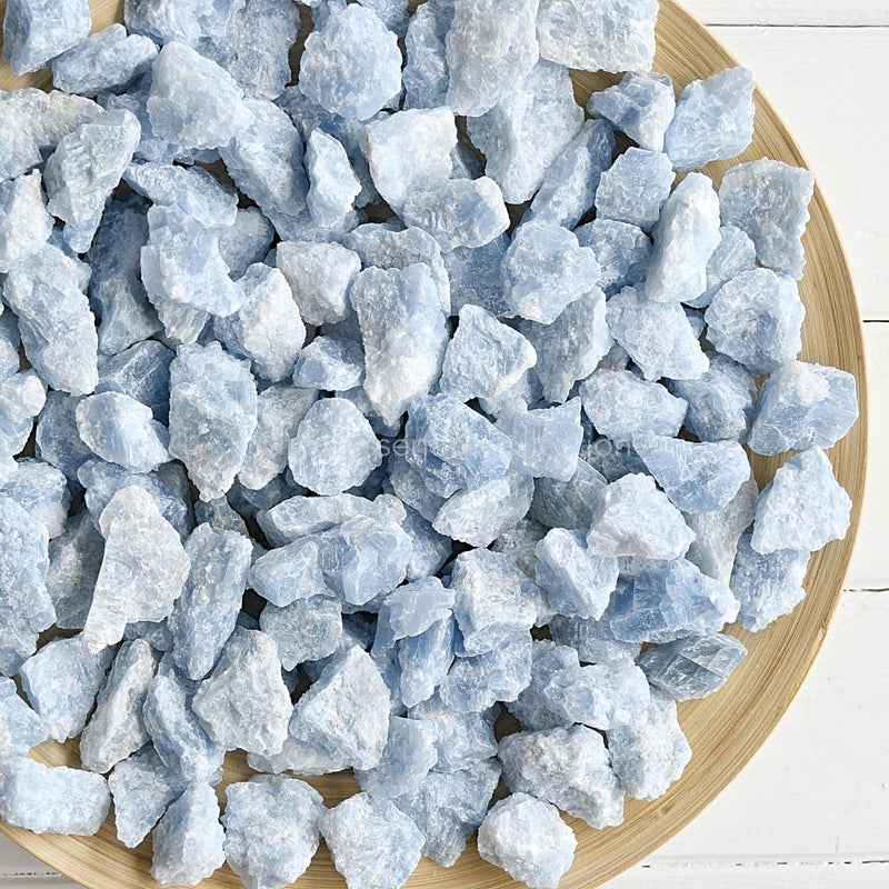 raw rough blue calcite crystals gemstones in wooden bowl white background