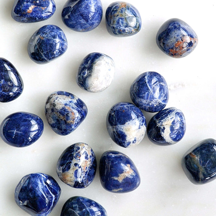 sodalite tumbled crystals on white marble background